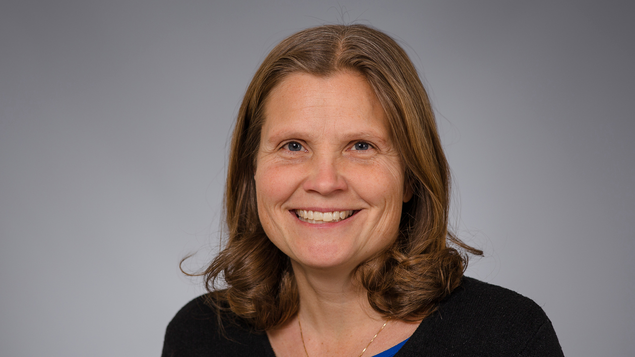 En leende kvinna i svart tröja och blå skjorta