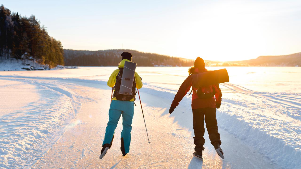 Två personer åker skridskor på en sjö.