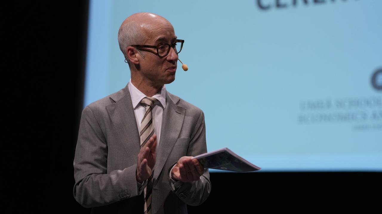 A man stands in front of a projection screen.