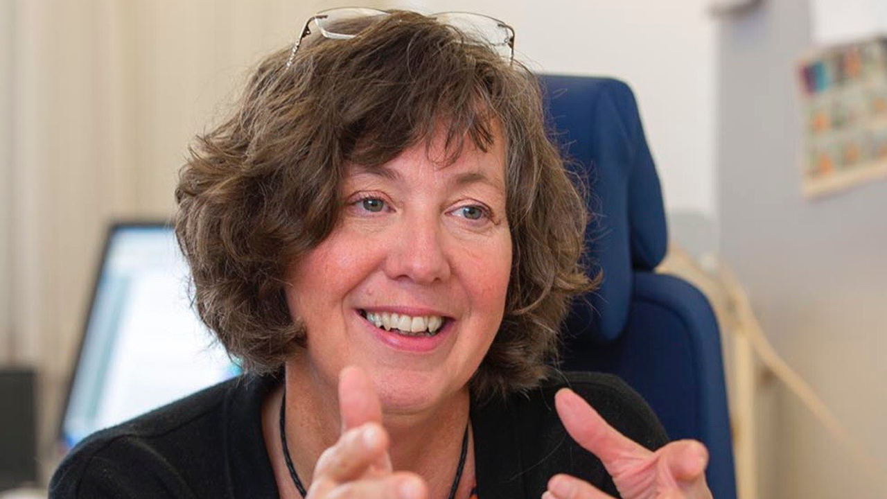 Närbild på Beatrice Melin, professor och överläkare, när hon håller upp båda händerna i nivå med hakan.