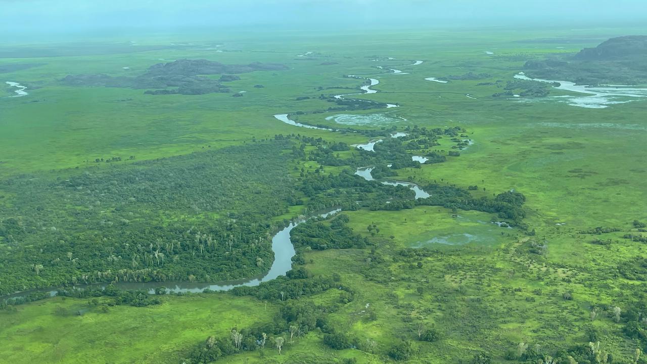 En flygbild av en flod som rinner genom ett grönskande fält.