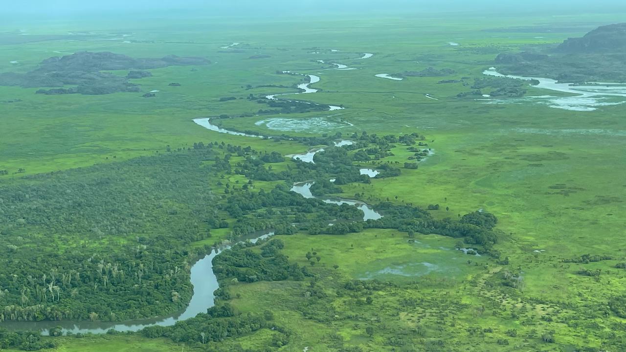 En flygbild av en flod som rinner genom ett grönskande fält.