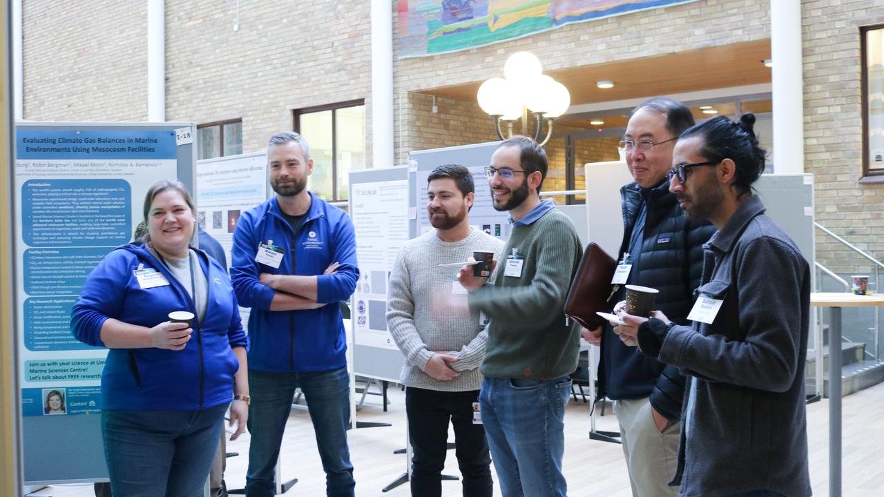 A group of people standing in front of the posters in the conference venue