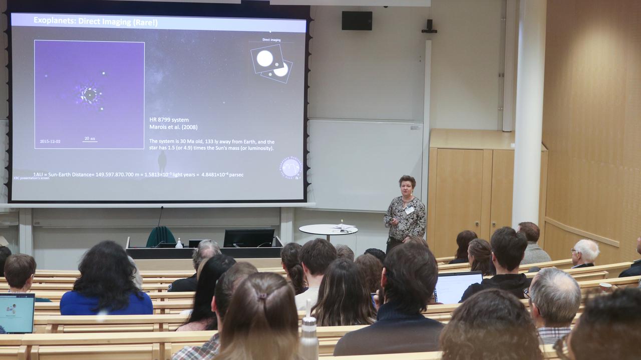 Participants of a scientific conference listening to the lecture given by a female researcher