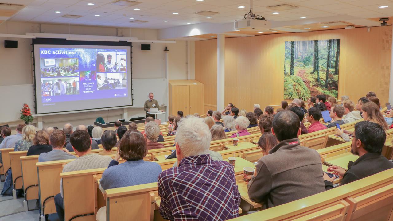 The presenter is talking to the audience in the lecture hall