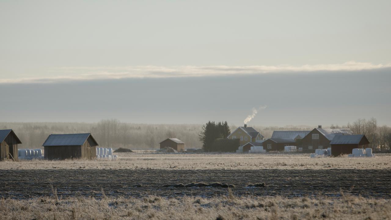Lador och boningshus med åkerfält i förgrunden.