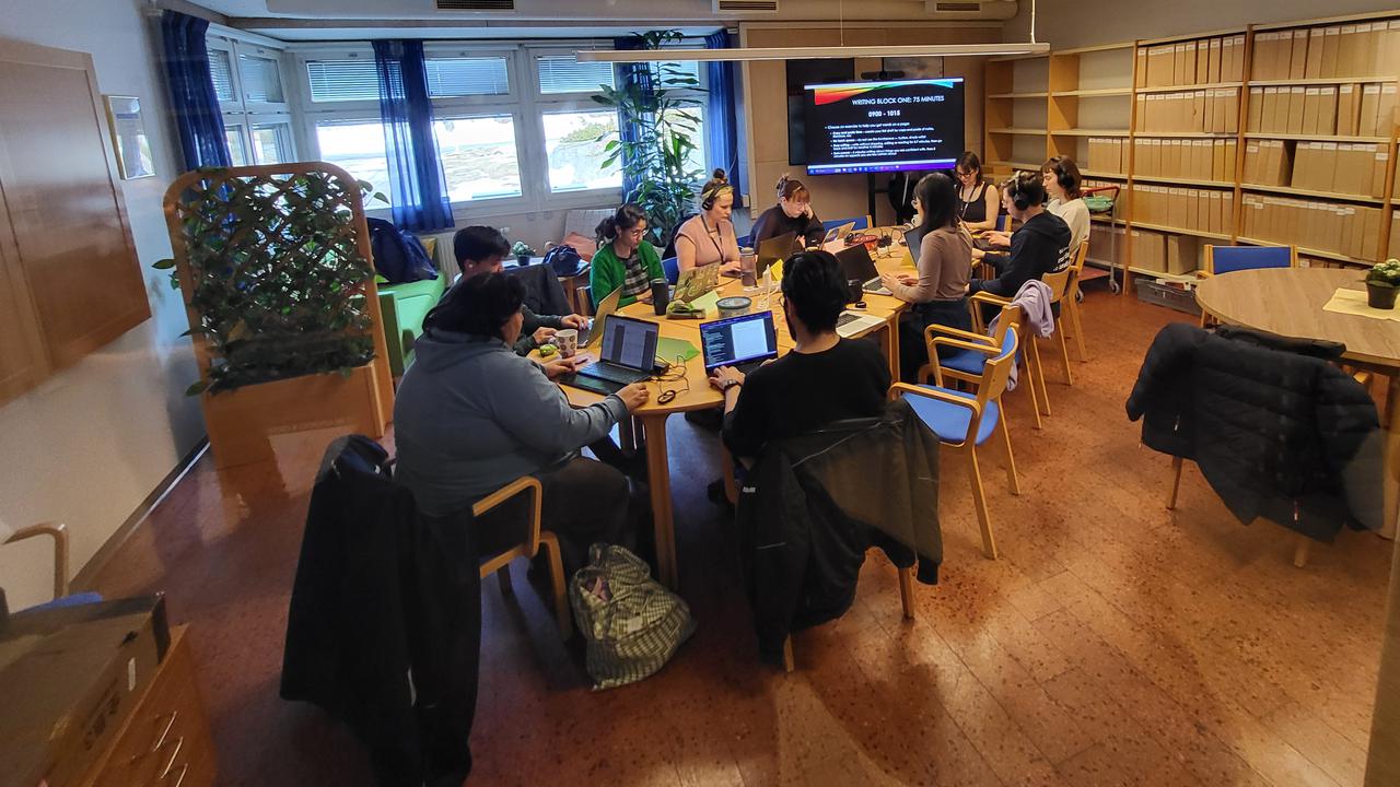 Personer sitter och arbetar runt ett bord.