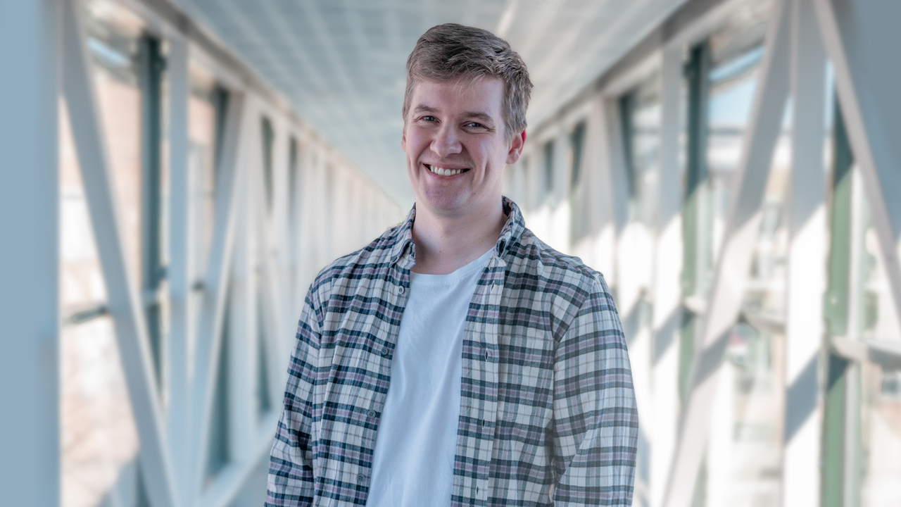 En man står på en bro med händerna i fickorna