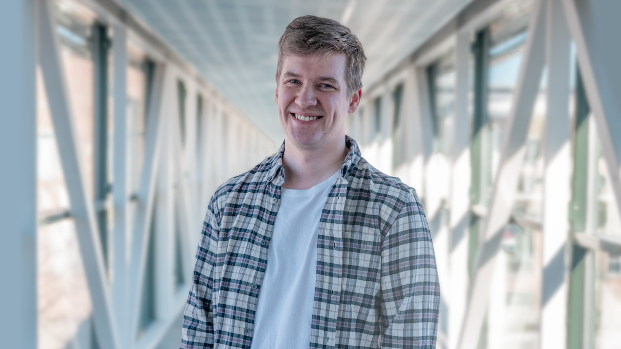 En man står på en bro med händerna i fickorna