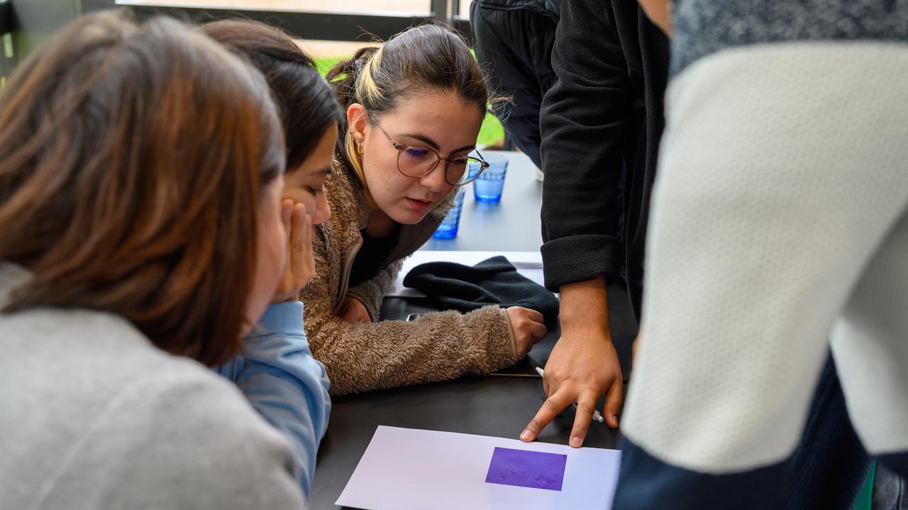 A group of people sitting around a table looking at a purple image.