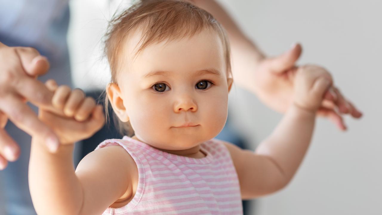 Liten flicka lär sig gå med hjälp av sin mamma.