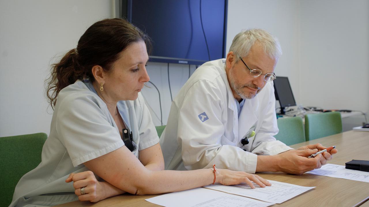 : I ett mötesrum sitter Karin Forsberg och Peter Andersen och diskuterar samtidigt som de tittar på några papper med provsvar som ligger på bordet framför dem.