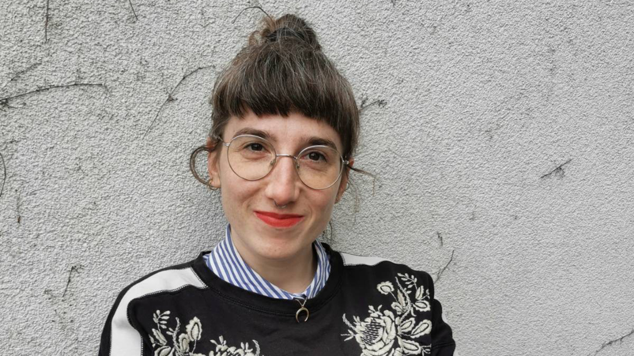 Kvinna som är gästforskare vid Umeå universitet sitter lutat mot en betongvägg.