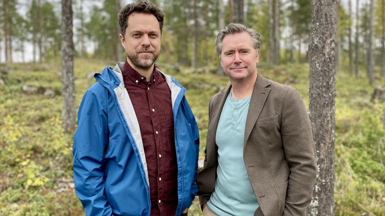 Två män som står bredvid varandra i en skog.