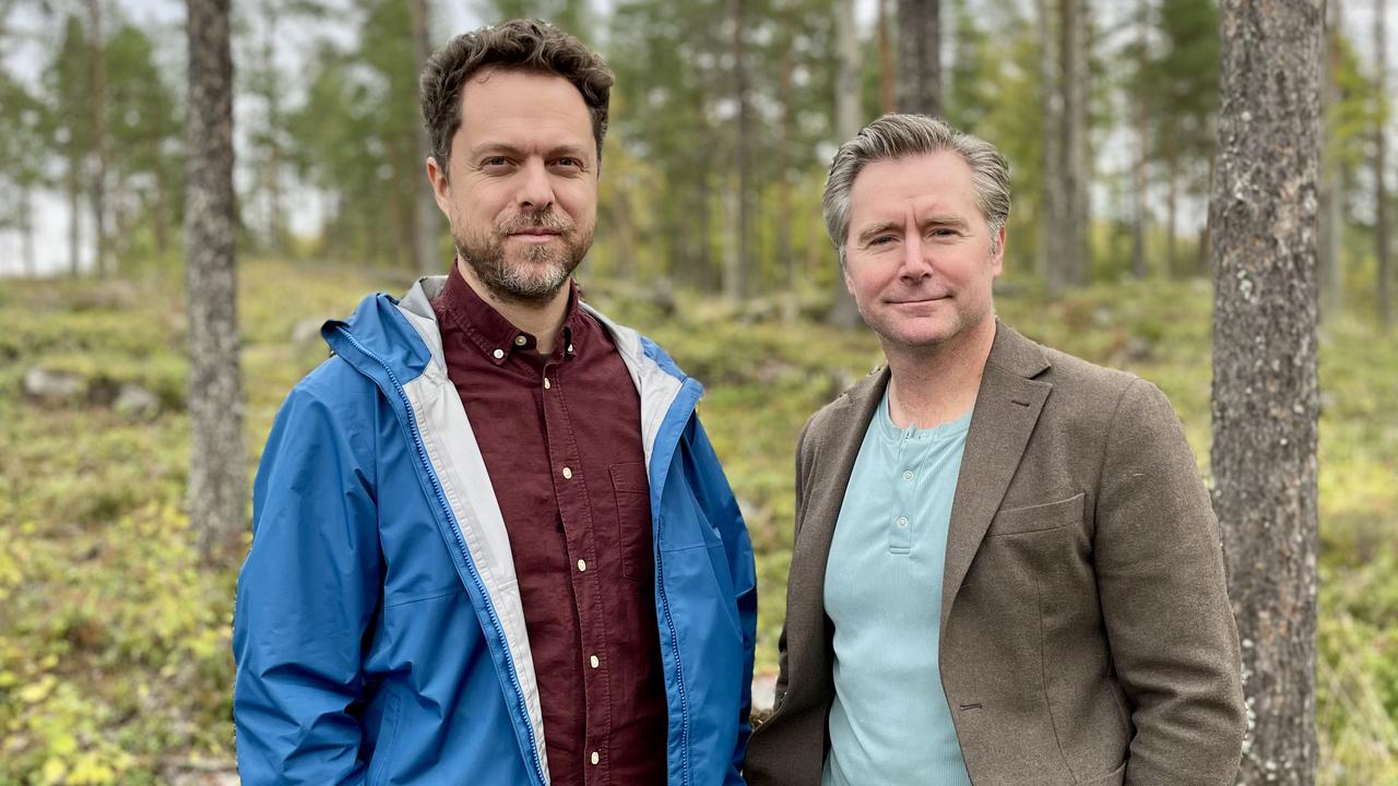 Två män som står bredvid varandra i en skog.