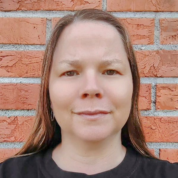 En kvinna som står framför en tegelvägg.