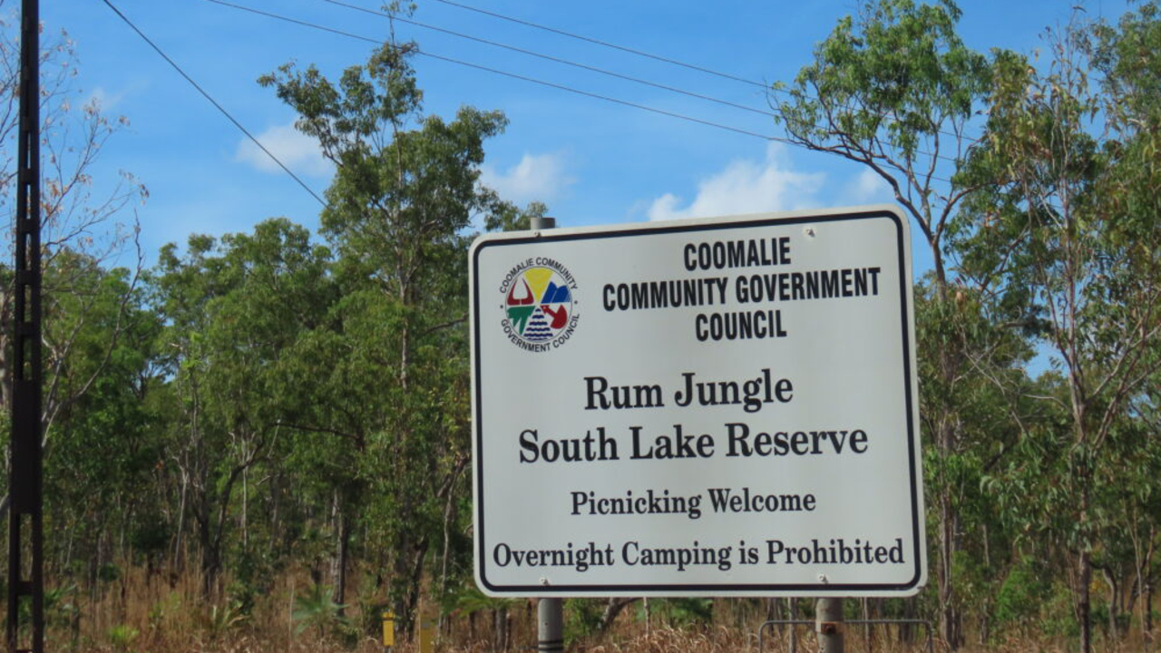 En vit skylt som sitter mitt i en skog