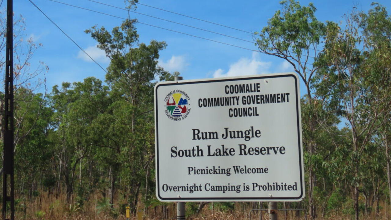 En vit skylt som sitter mitt i en skog