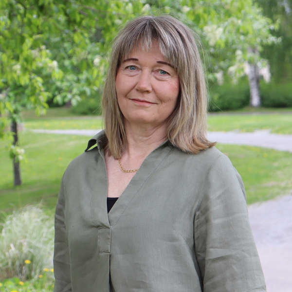 En kvinna står framför ett träd i en park.