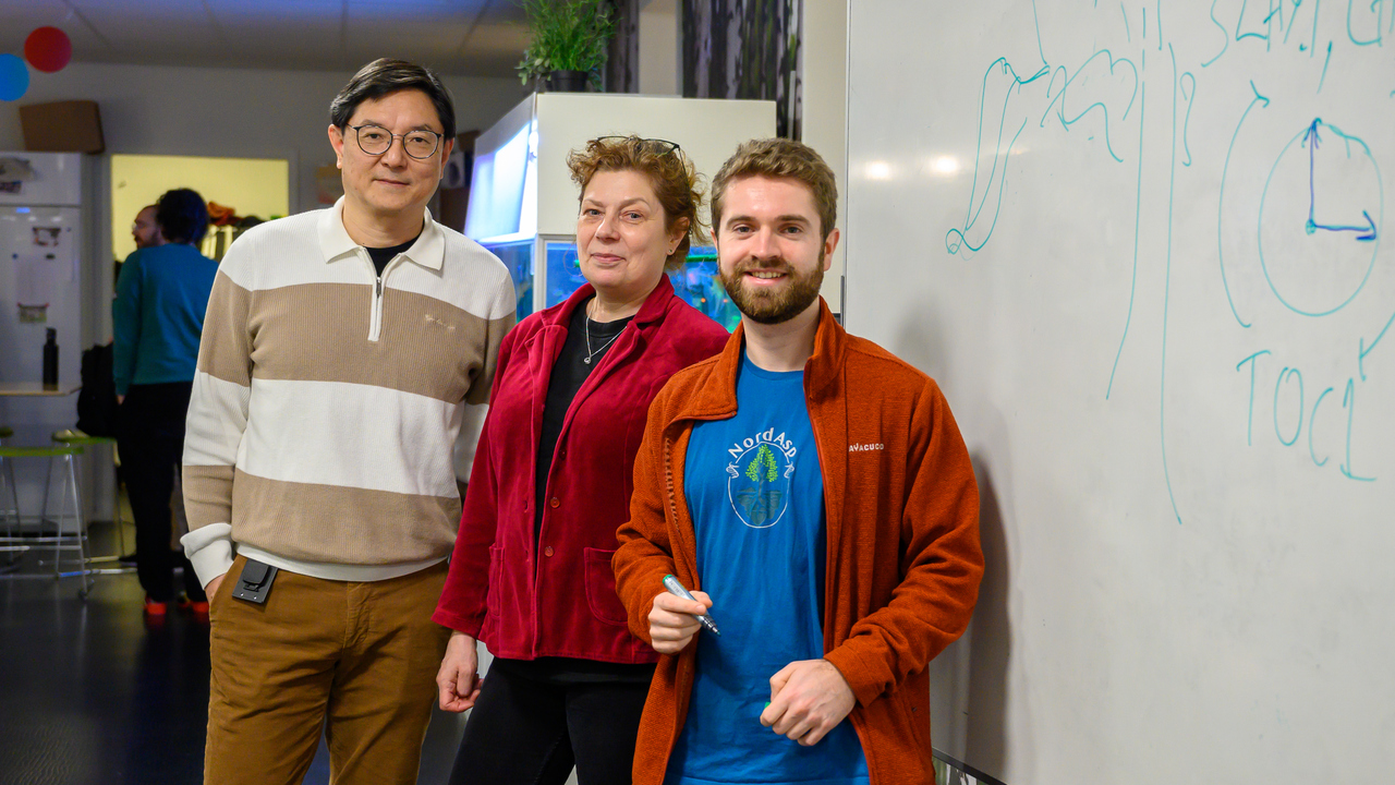 A group of people standing next to a white board