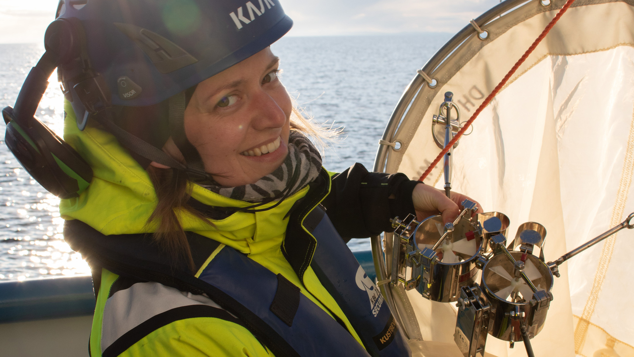 En person med skyddshjälm och gul overall ser glad ut när hon monterar utrustning på en stor håv.