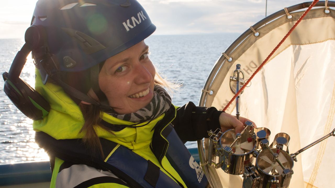 En person med skyddshjälm och gul overall ser glad ut när hon monterar utrustning på en stor håv.