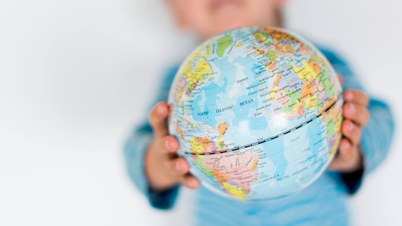 Barn håller upp en liten jordglob mellan sina händer.