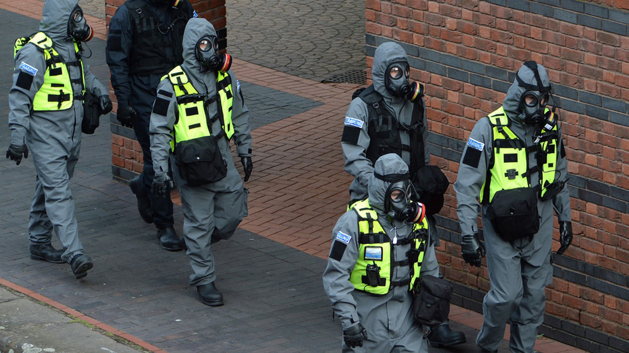 Personer iklädda skyddskläder och gasmasker under en beredskapsövning.