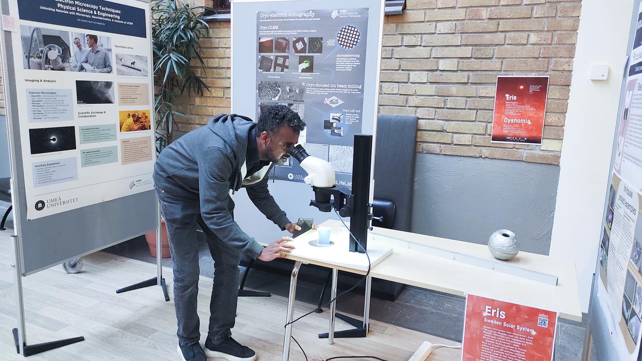 A man looking through a stereo microscope 