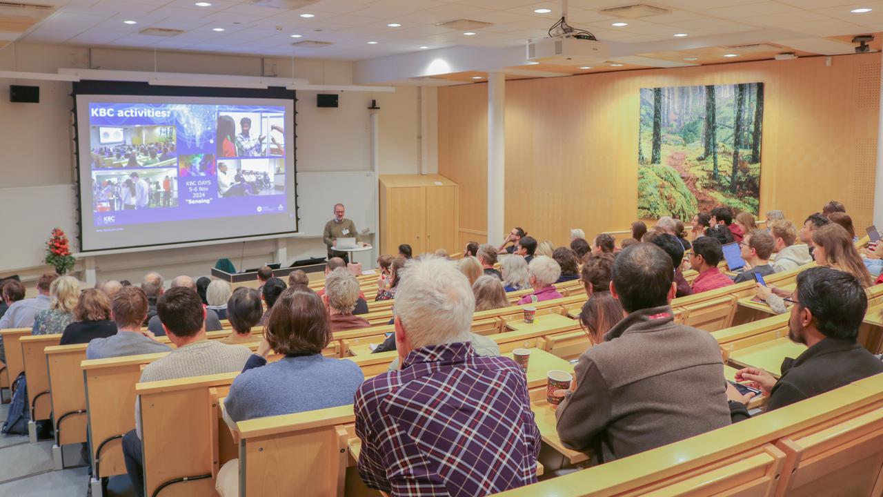 The presenter is talking to the audience in the lecture hall