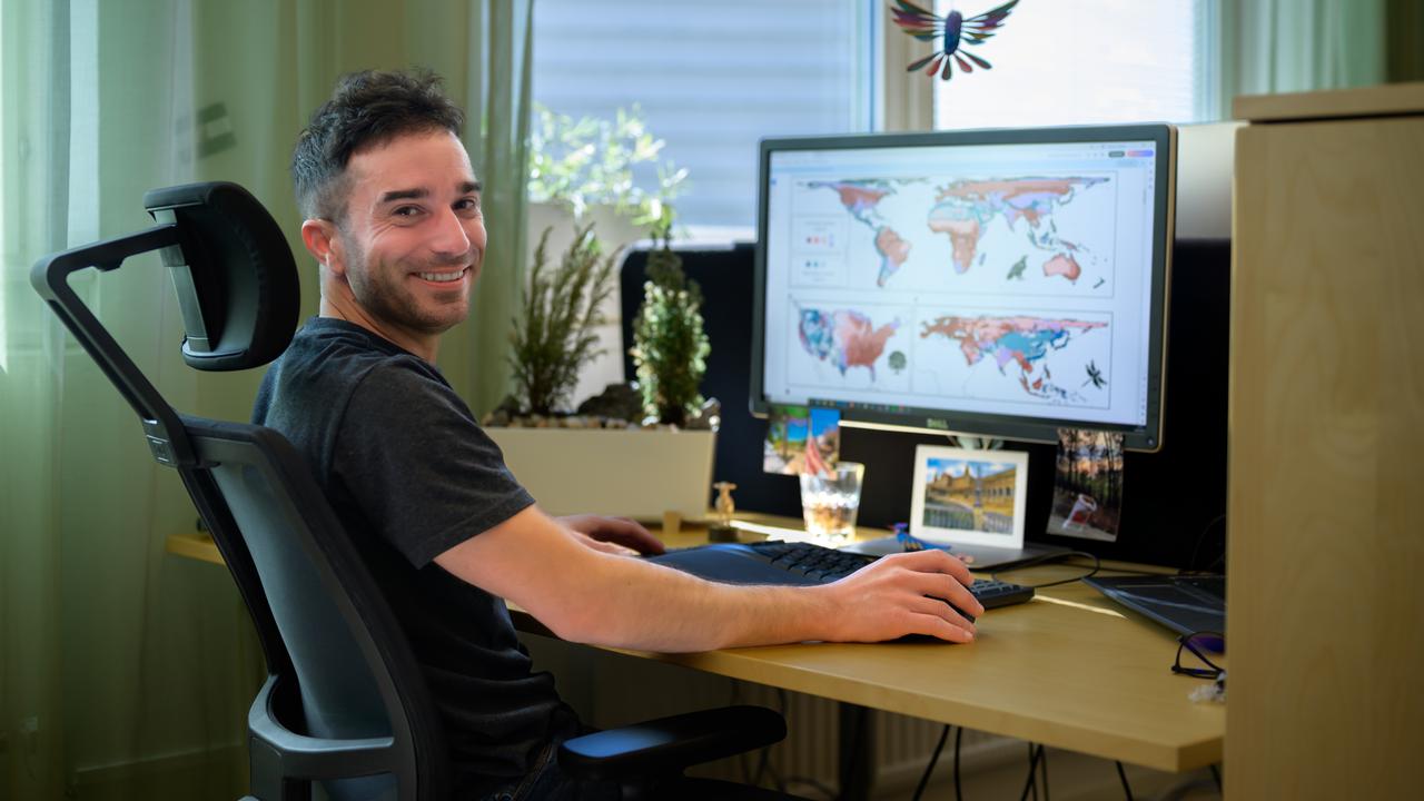 En man sitter vid ett skrivbord med en dator.