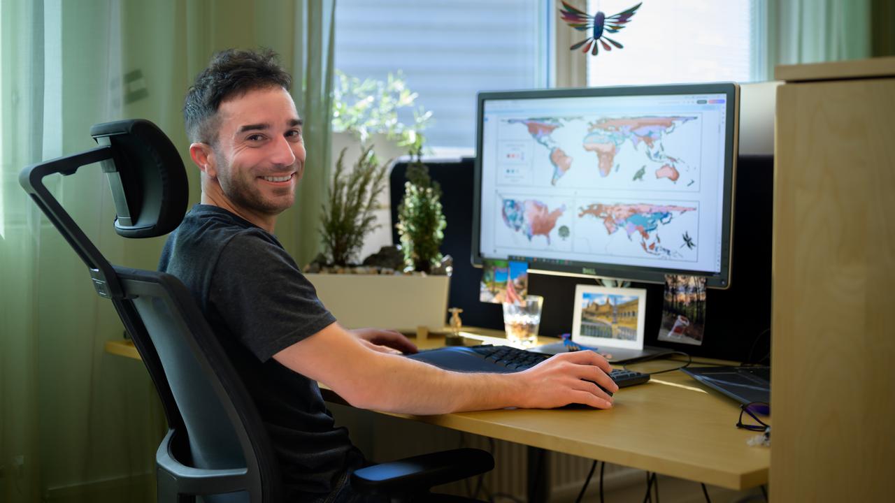 En man sitter vid ett skrivbord med en dator.