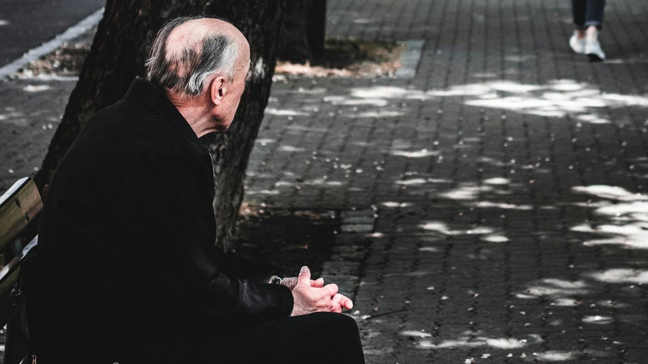 An elderly man is sitting on a bench.