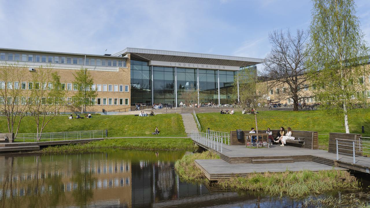 Lindellhallen och Samhällsvetarhuset sedda från campusdammen på våren.