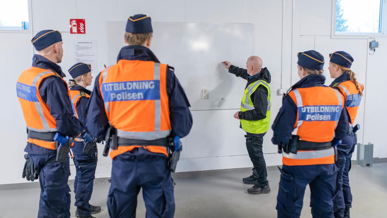 Polislärare Conny Tärnklev instruerar polisstudenter vid vita tavlan i Polisutbildningshusets garage.