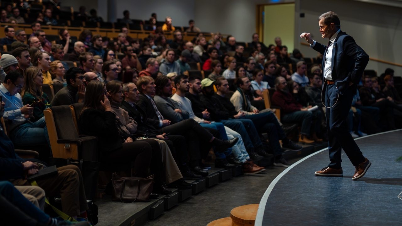 En man står längst fram på scenen inför en stor publik.