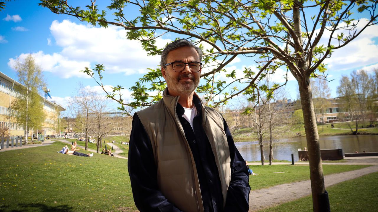 En man som står bredvid ett träd på campus.