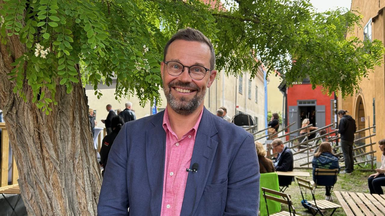 Man i kavaj framför träd. I Almedalen på Gotland.