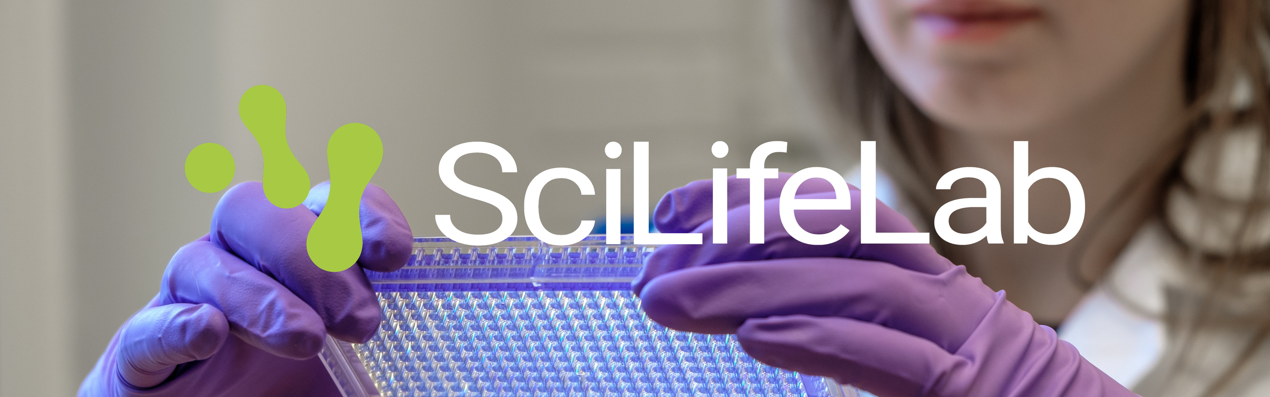 En kvinna i labbrock och lila handskar håller i en mikrochick