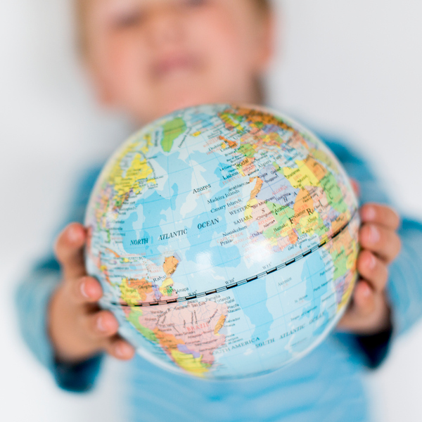 Barn håller upp en liten jordglob mellan sina händer.