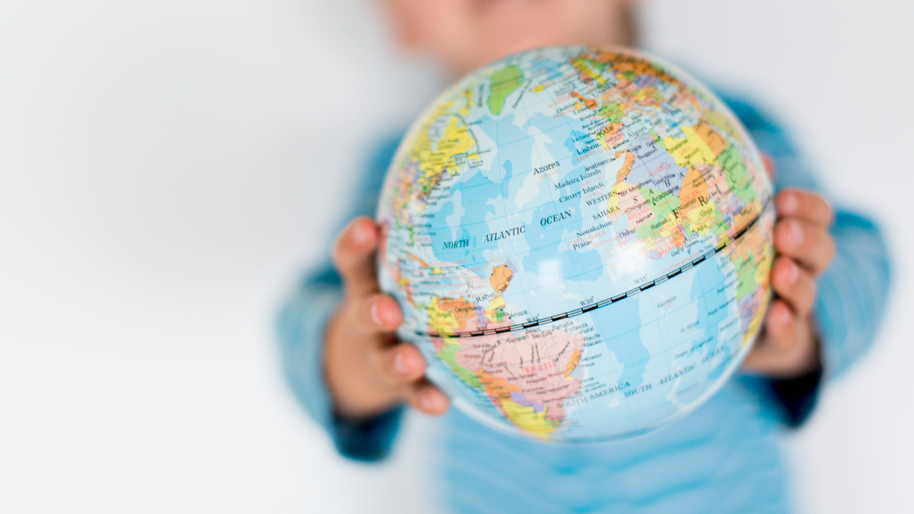 Barn håller upp en liten jordglob mellan sina händer.