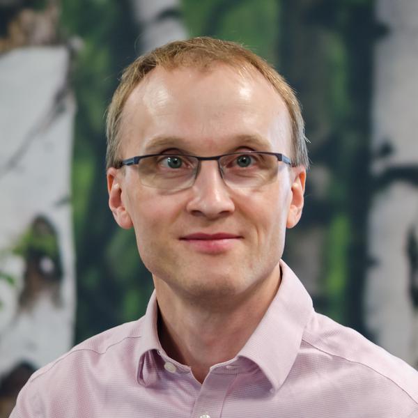 A man wearing glasses standing in front of a painting