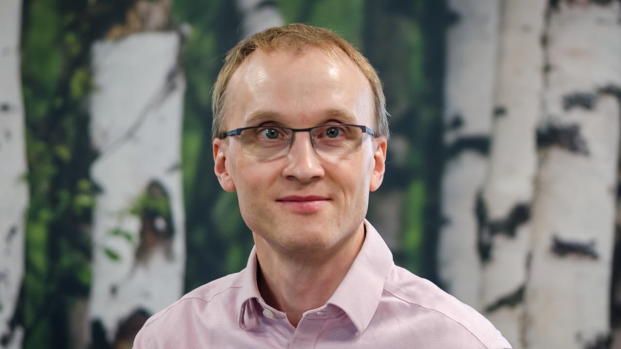 A man wearing glasses standing in front of a painting