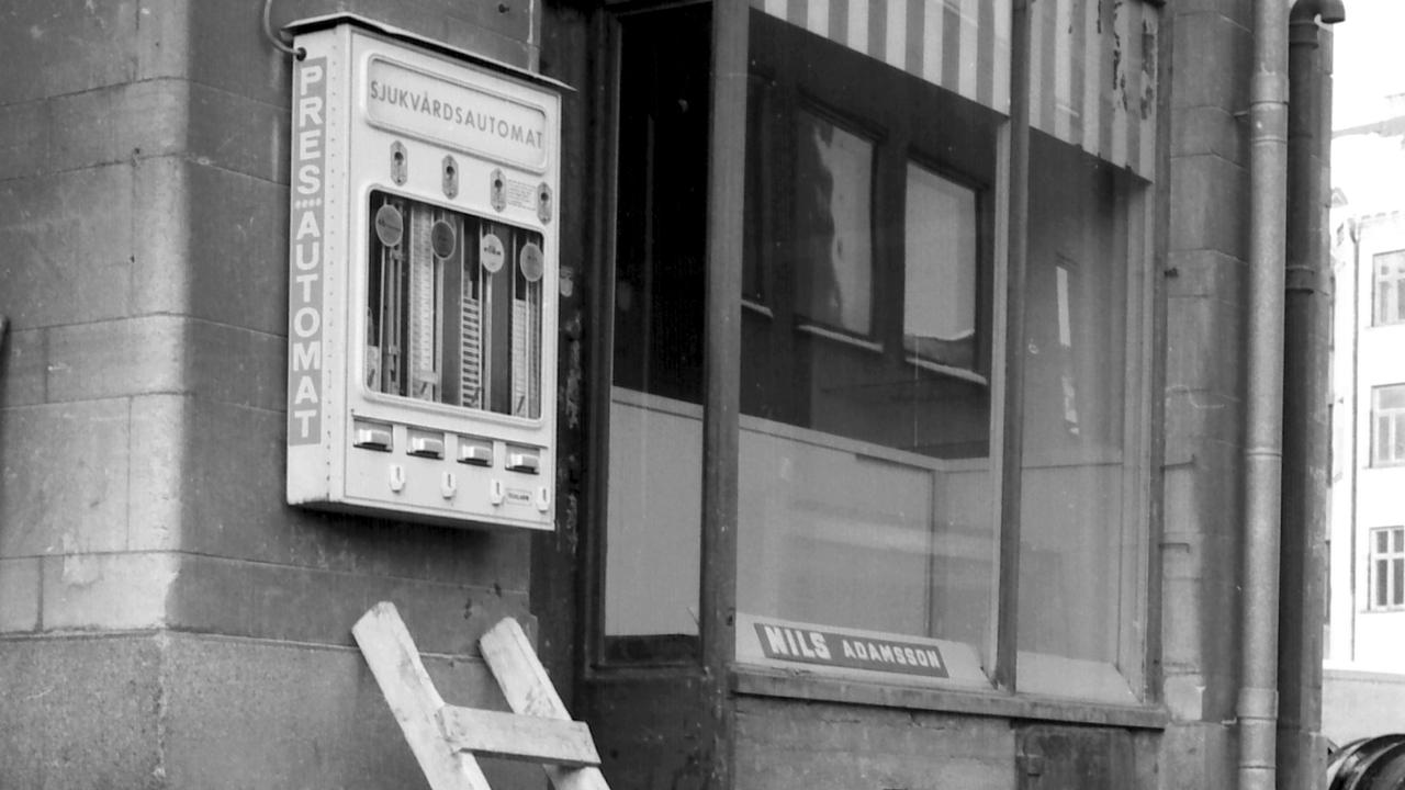 Kondomautomat på en vägg brevid Nils Abrahamssons affär. En stege går upp mot kondomautomaten.