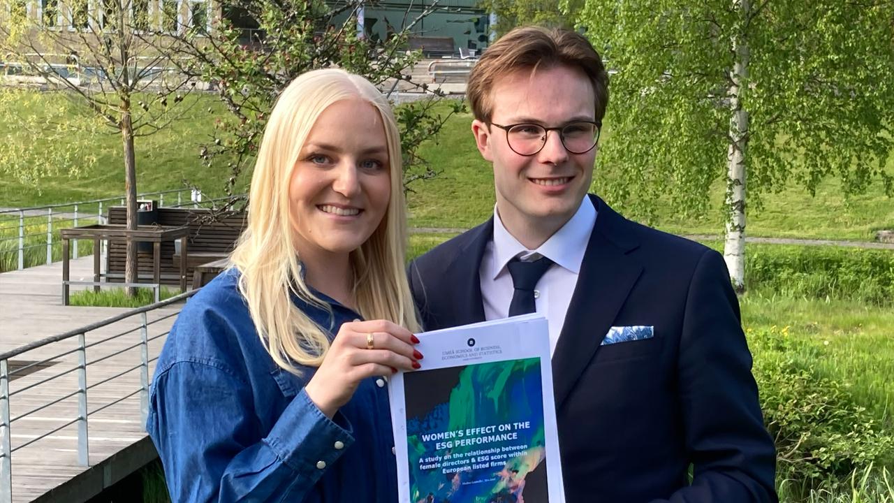 En man och en kvinna håller upp sin uppsats.