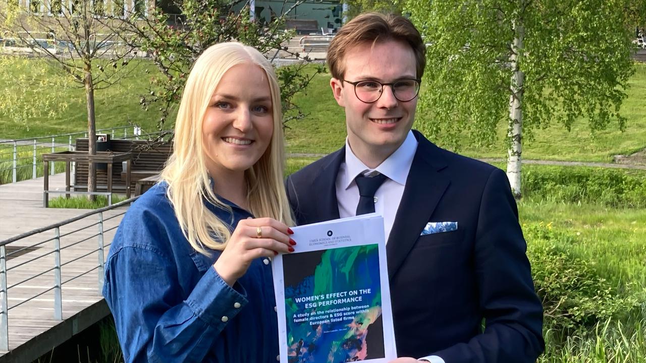 En man och en kvinna håller upp sin uppsats.