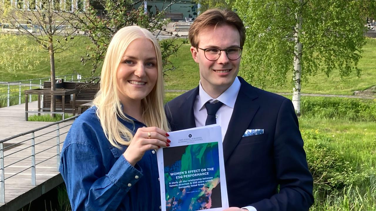 A man and a woman holding up their thesis.