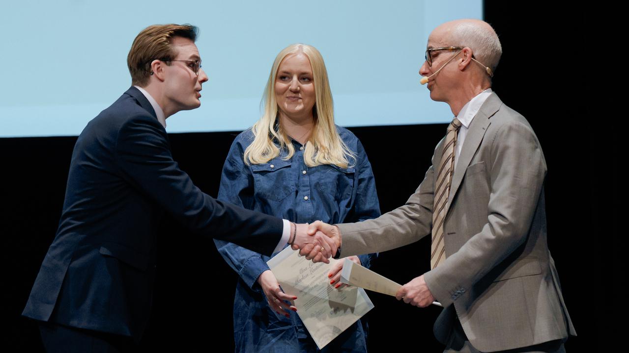 Two men and a woman shake hands on stage.