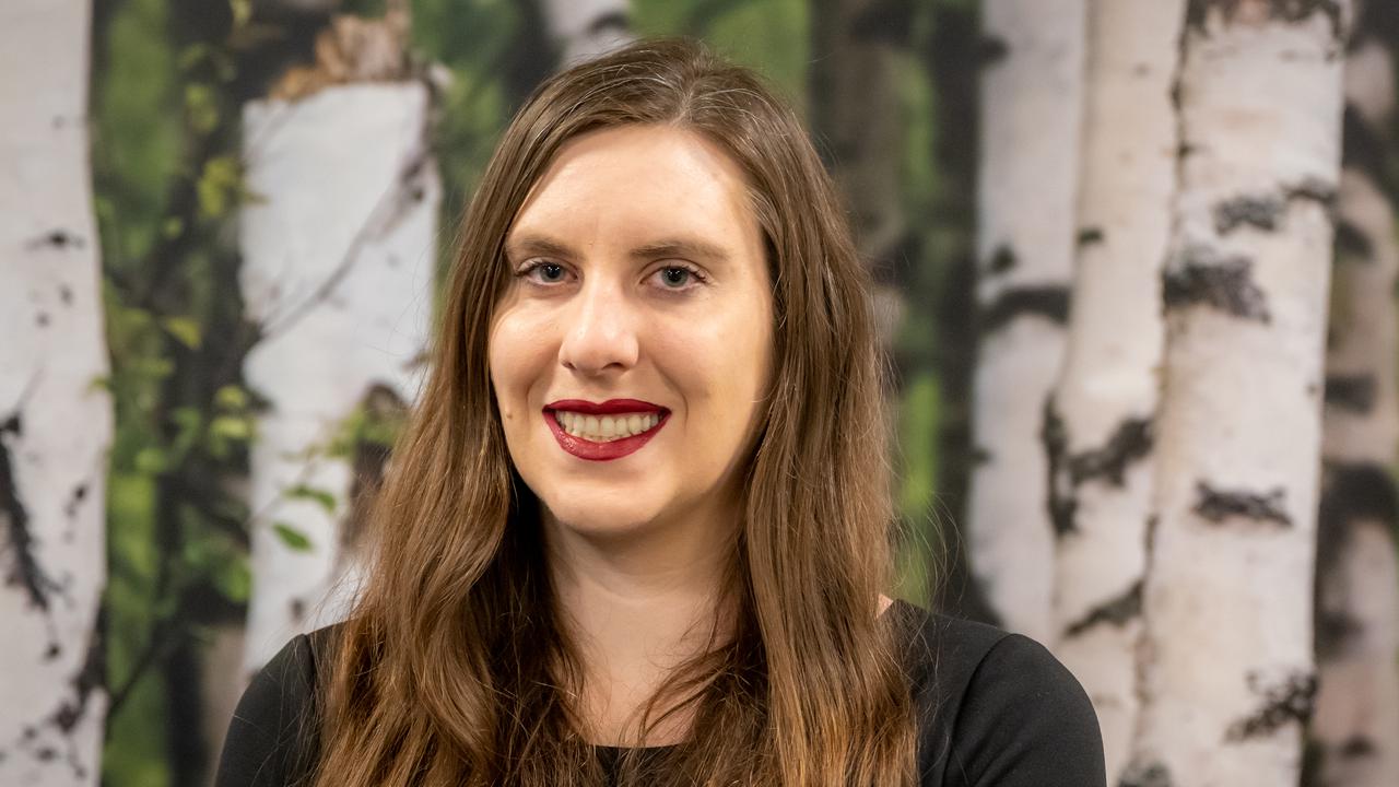 A woman with long hair standing in front of trees