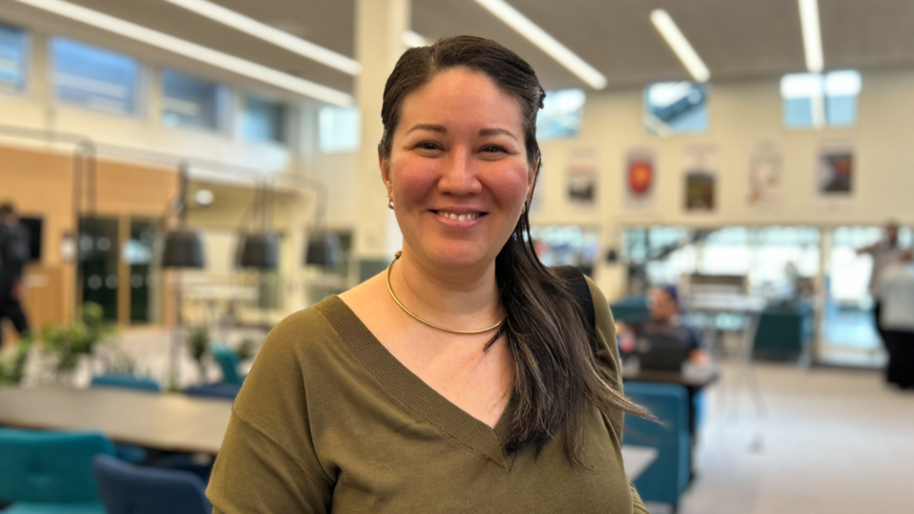 Kvinna ler mot kameran i konferenslokal.